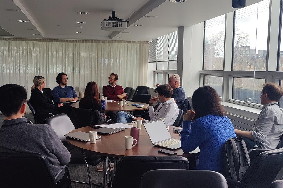 Nine people sitting around two tables in discussion at a workshop
